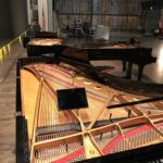 Three Steinway concert grand pianos (with lids removed) sharing one stage.
